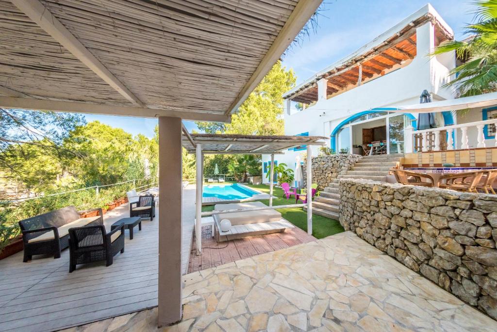 un patio con mesa, sillas y pared de piedra. en VILLA MONTECRISTO., en Montecristo