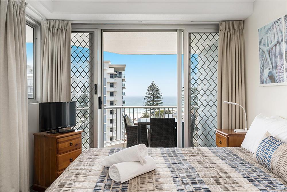 um quarto com uma cama e vista para uma varanda em Rainbow Bay Resort Holiday Apartments em Gold Coast