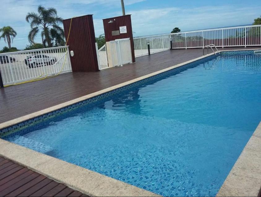 una gran piscina azul con terraza de madera en AP de Praia Mar Azul - Praia da Vila, en Imbituba