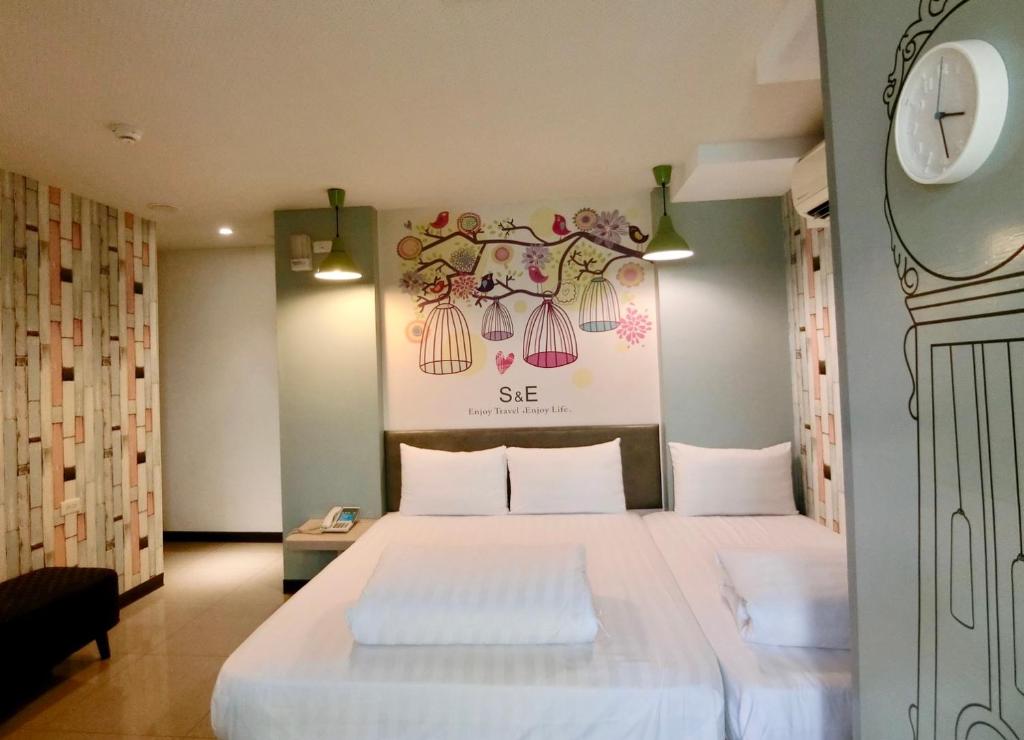 a bedroom with a white bed and a clock on the wall at S&amp;E Hotel in Tainan