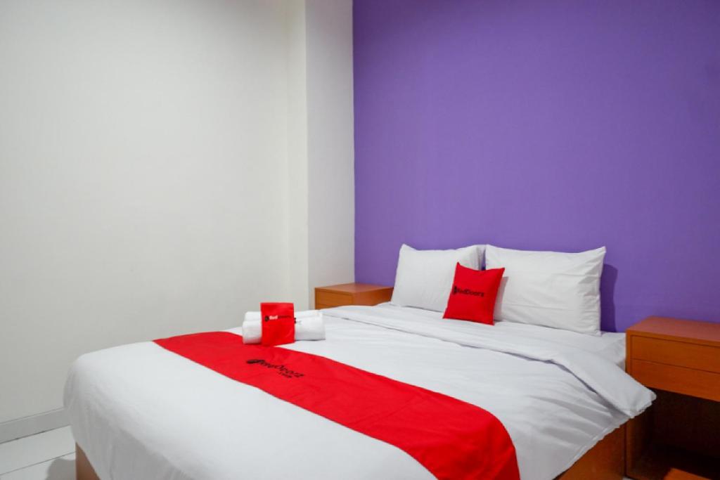 a bedroom with a large bed with red and white pillows at RedDoorz near Alun Alun Kaliwungu Kendal in Brangsong