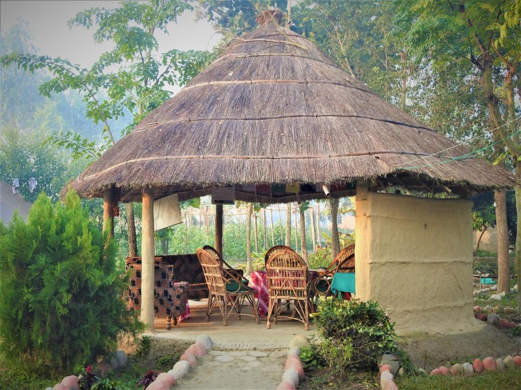 a gazebo with chairs and a straw roof at Royal Tiger Cottage in Bhurkīā
