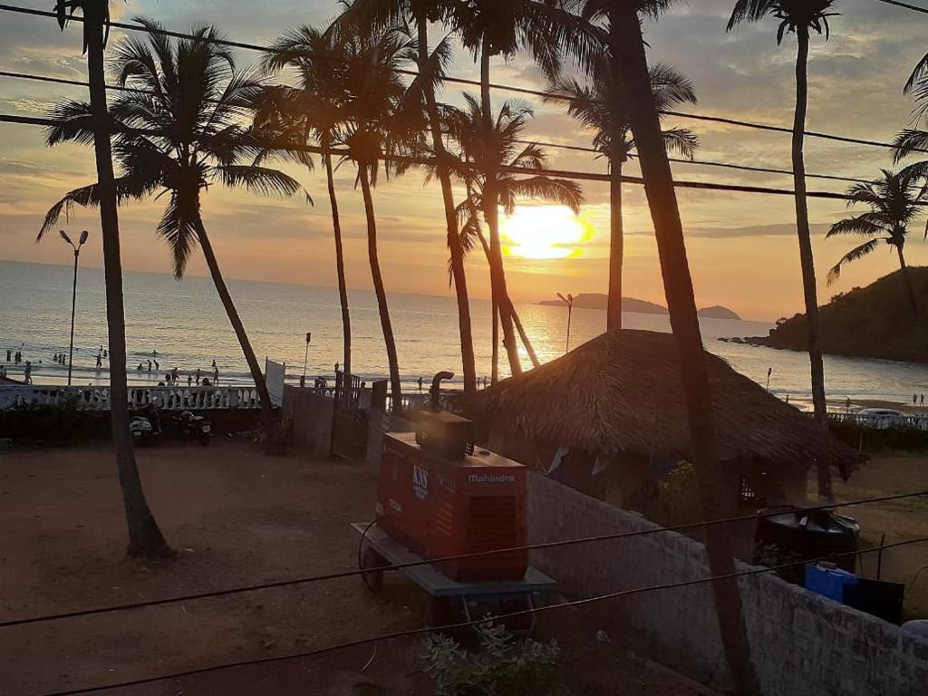 zachód słońca na plaży z palmami i oceanem w obiekcie Leon Hide Out Guest House w mieście Vasco Da Gama