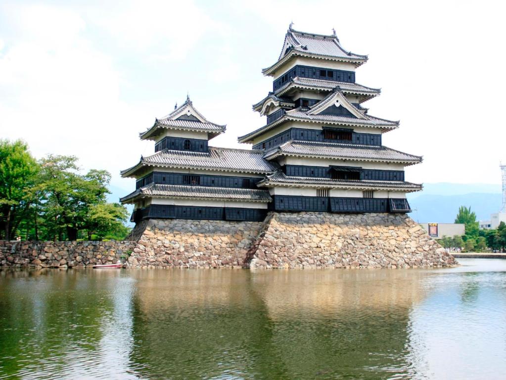 a large building sitting on top of a body of water at Hakuraiso in Matsumoto