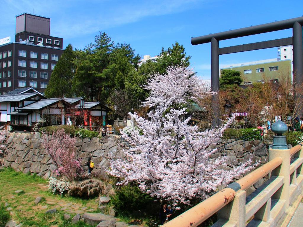 a tree with pink flowers next to a fence at Hakuraiso in Matsumoto
