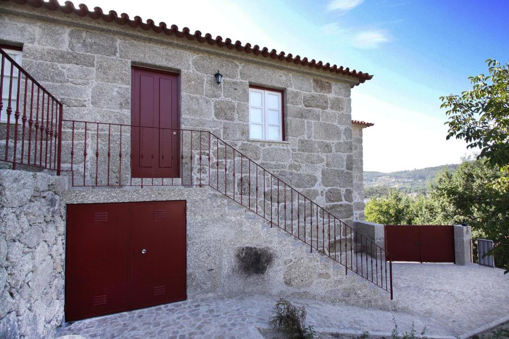 a stone house with red doors and a staircase at Casa Oceane in Duquezas