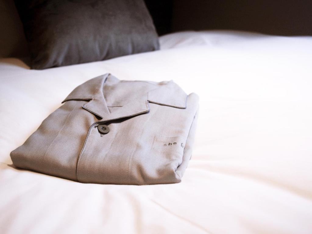 a brown jacket sitting on top of a white bed at the b ikebukuro in Tokyo