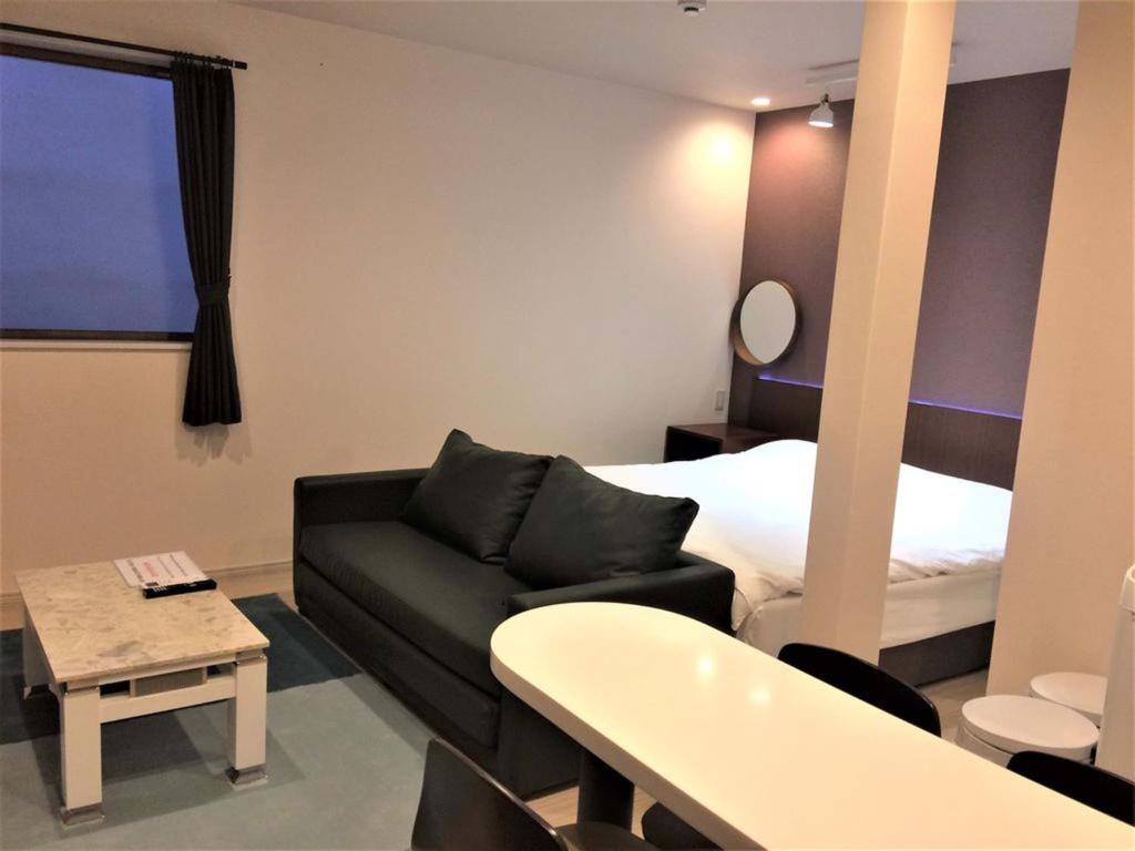Habitación de hotel con sofá y cama en 玉出103 wifi付 玉出駅から徒歩2分 地下鉄難波迄8分, en Osaka