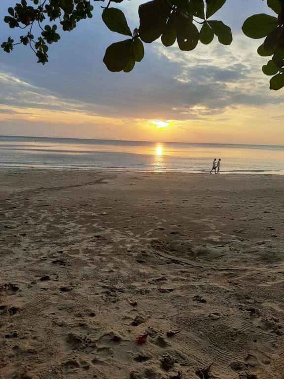 two people walking on the beach at sunset at Cha Cha Bungalow in Ko Jum