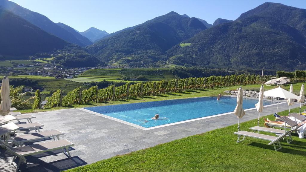 uma piscina com cadeiras e montanhas ao fundo em Hotel Pacherhof em Bressanone