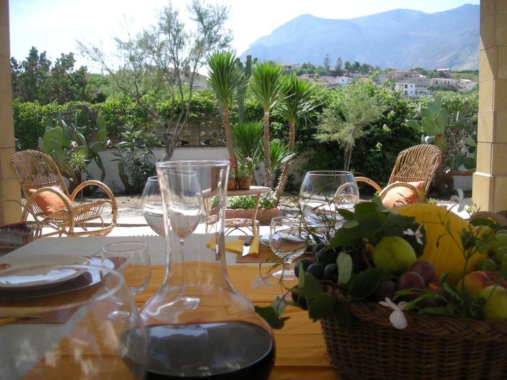 a table with wine glasses and a basket of fruit at Villa On The Beach "Spiaggia Plaia" in Castellammare del Golfo