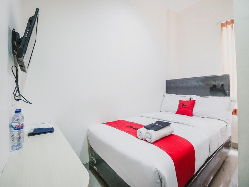 um quarto branco com uma cama e uma televisão. em RedDoorz Plus near Mall Ciputra Jakarta em Jakarta