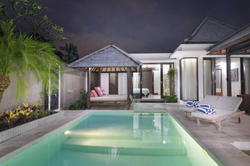 a swimming pool in a backyard with a villa at Villa Hibiscus in Sanur
