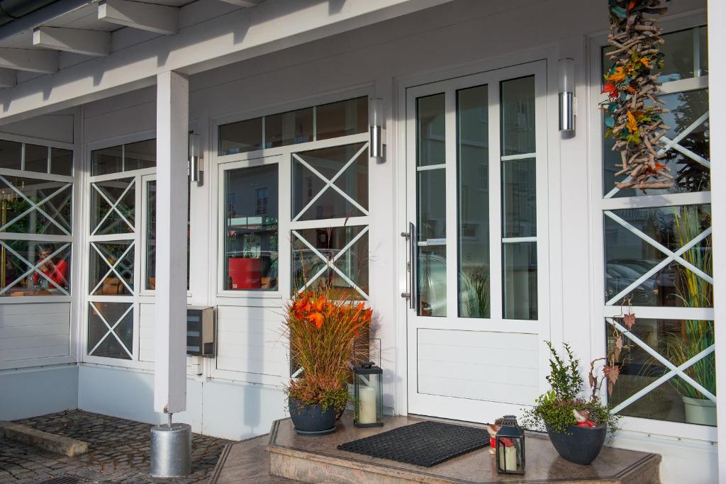 een veranda met glazen deuren en potplanten bij Hotel Angermeier GARNI in Eching