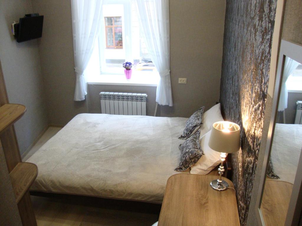 ein kleines Schlafzimmer mit einem Bett und einem Tisch mit einer Lampe in der Unterkunft Апартаменты на ул.Шопена in Lwiw