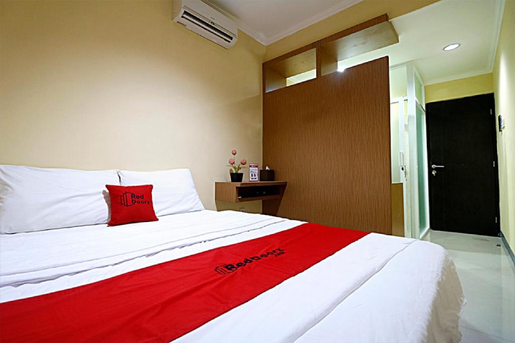 RedDoorz near ITC Cempaka Mas في جاكرتا: غرفة نوم مع وسادة حمراء على سرير