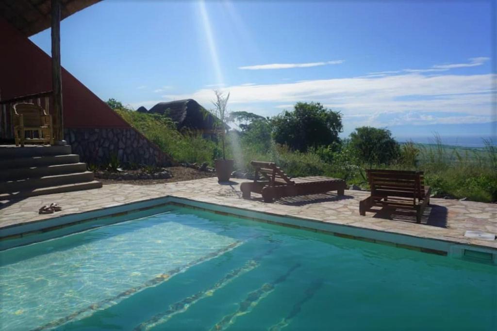 a swimming pool with two chairs and a table at Kikonko Lodge in Biseruka