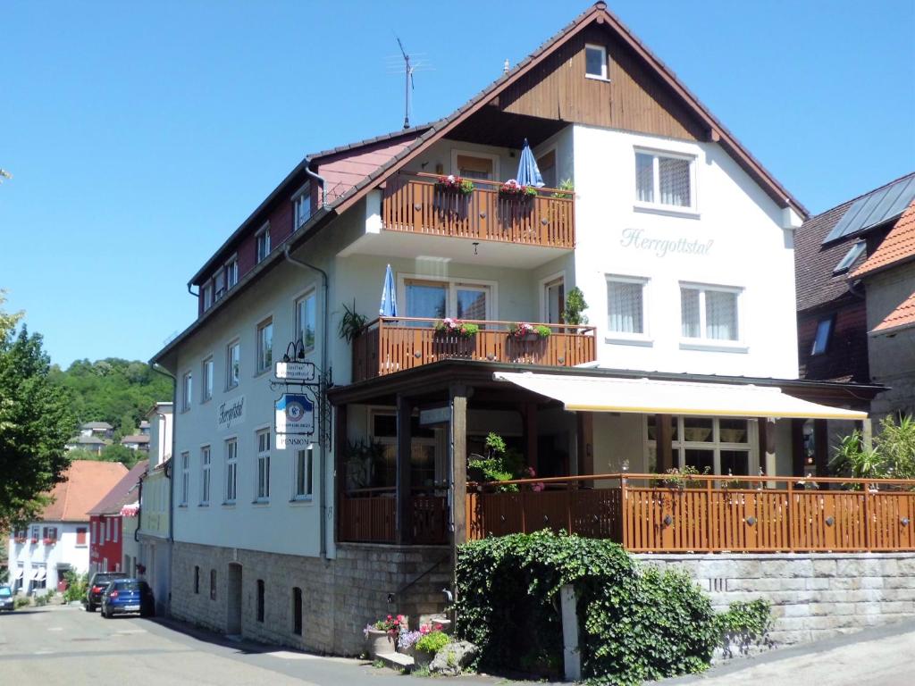 a large white building with a balcony at Restaurant - Pension Herrgottstal in Creglingen