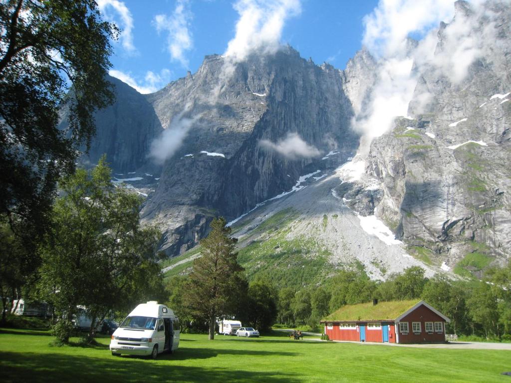 a small cabin with a mountain range and mountains at Trollveggen Camping in Åndalsnes