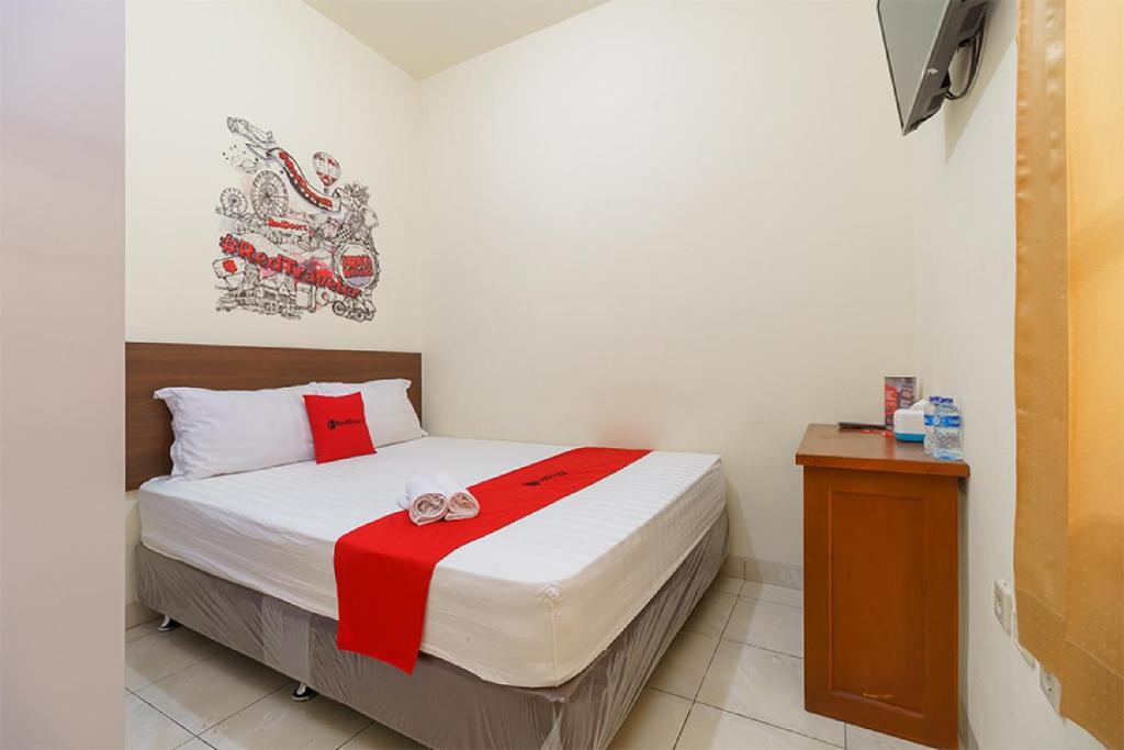 una camera con un letto con una coperta rossa e bianca di RedDoorz @ Tanjung Duren a Giacarta