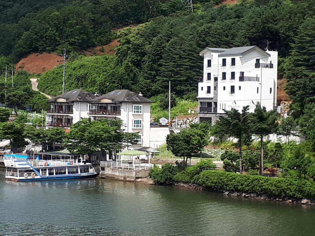 a large white building and a boat in the water at Interlaken Stay in Gapyeong