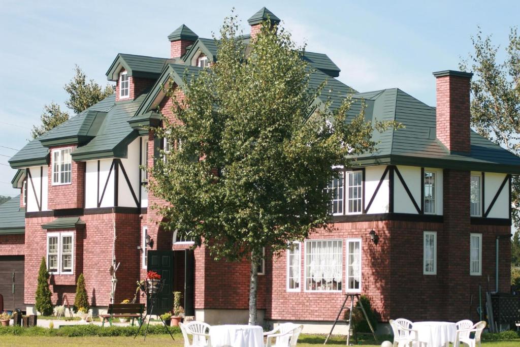 a large brick house with white chairs in front of it at Agri In Holiday in Hirosaki