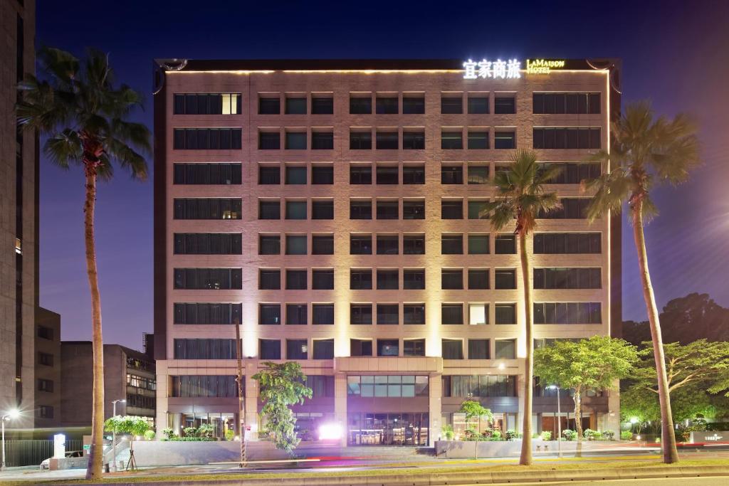 a tall building with palm trees in front of it at La Maison Hotel in Taipei