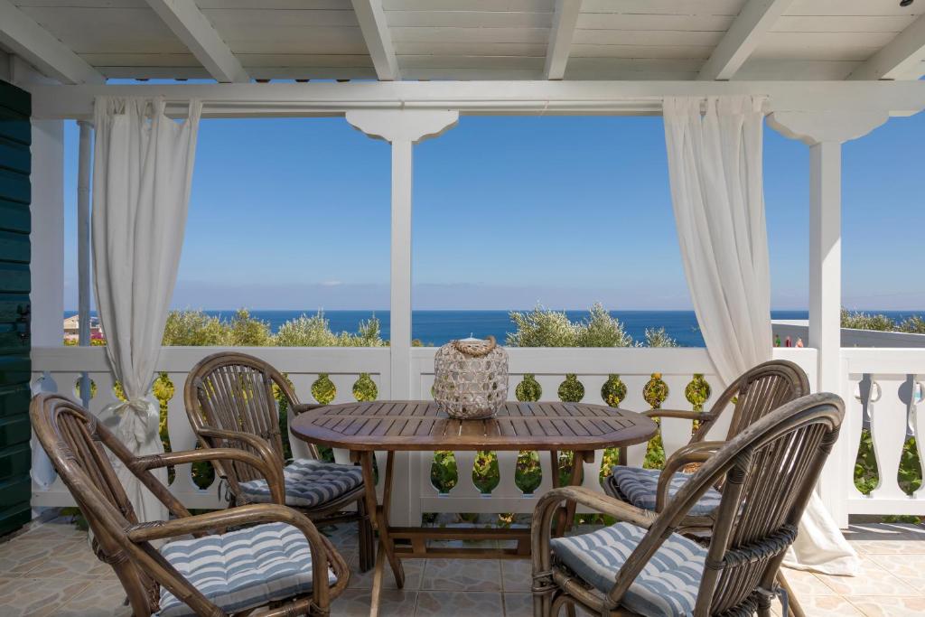 a table and chairs on a porch with a view of the ocean at Kostas Cottages in Agios Nikolaos