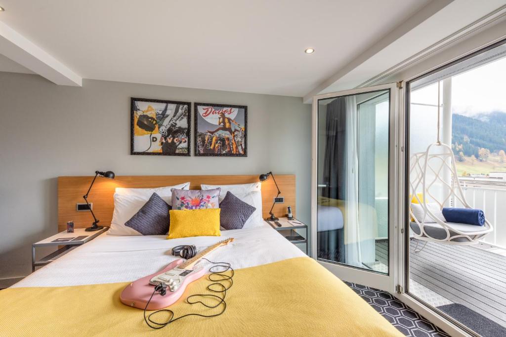 1 dormitorio con 1 cama grande y balcón en Hard Rock Hotel Davos en Davos