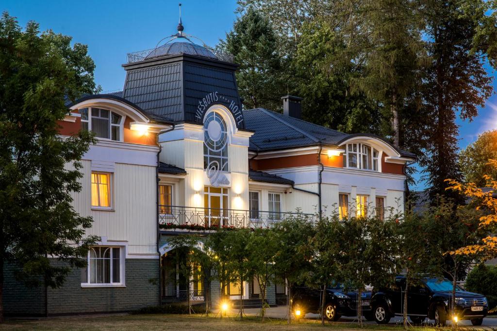 Una gran casa blanca con una torre encima. en Hotel Violeta, en Druskininkai