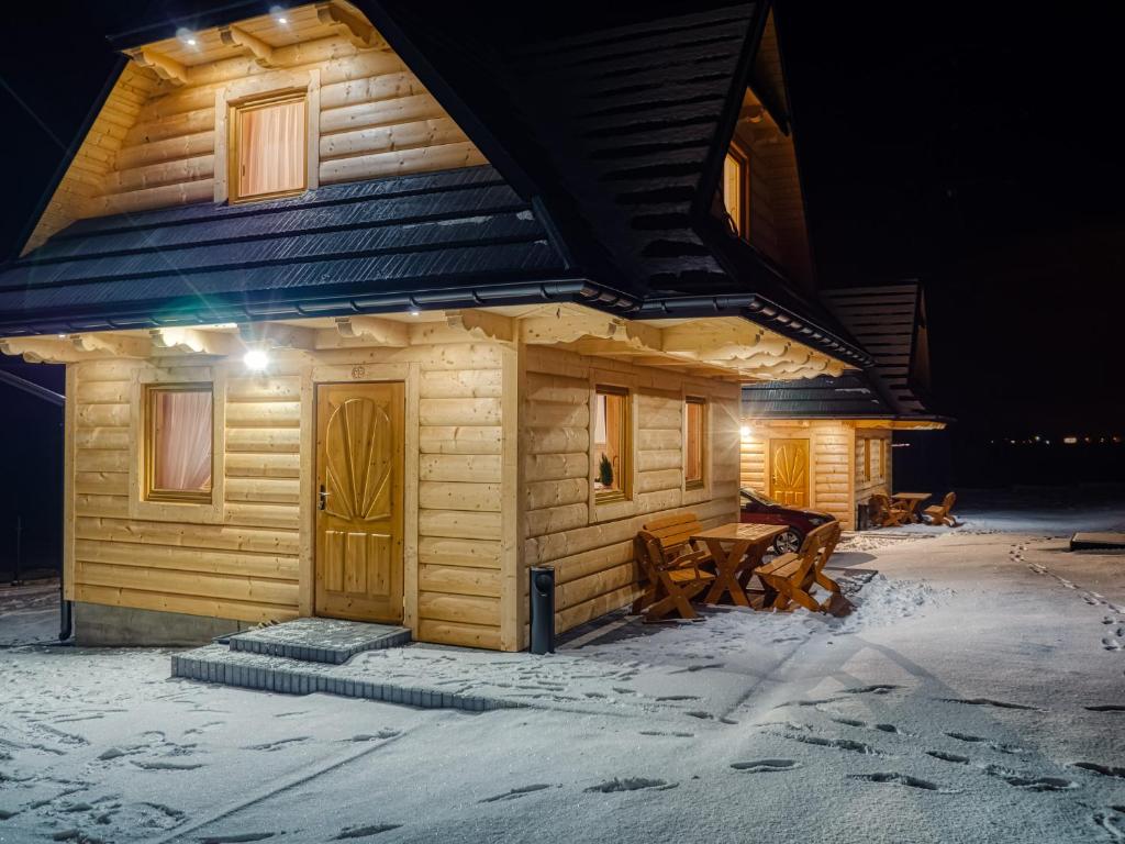 a log cabin in the snow at night at Domki Szarotki in Groń