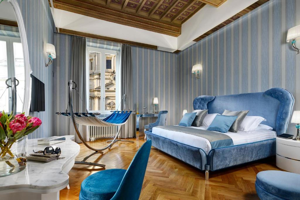 - une chambre avec un lit bleu, une table et des chaises dans l'établissement Lifestyle Suites Rome, à Rome