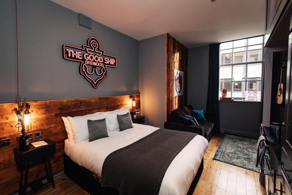 
a hotel room with a bed, chair, and nightstand at BrewDog Kennels - Aberdeen in Aberdeen
