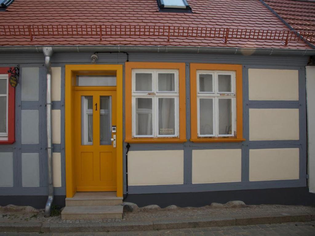 ein Haus mit gelber Tür und zwei Fenstern in der Unterkunft Töpferhof 1 in Tangermünde