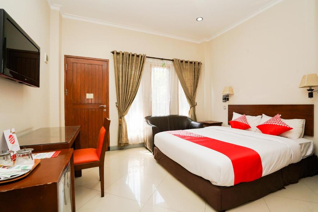 ein Hotelzimmer mit einem großen Bett und einem Schreibtisch in der Unterkunft Capital O 1430 Hotel Ratna Syariah in Probolinggo