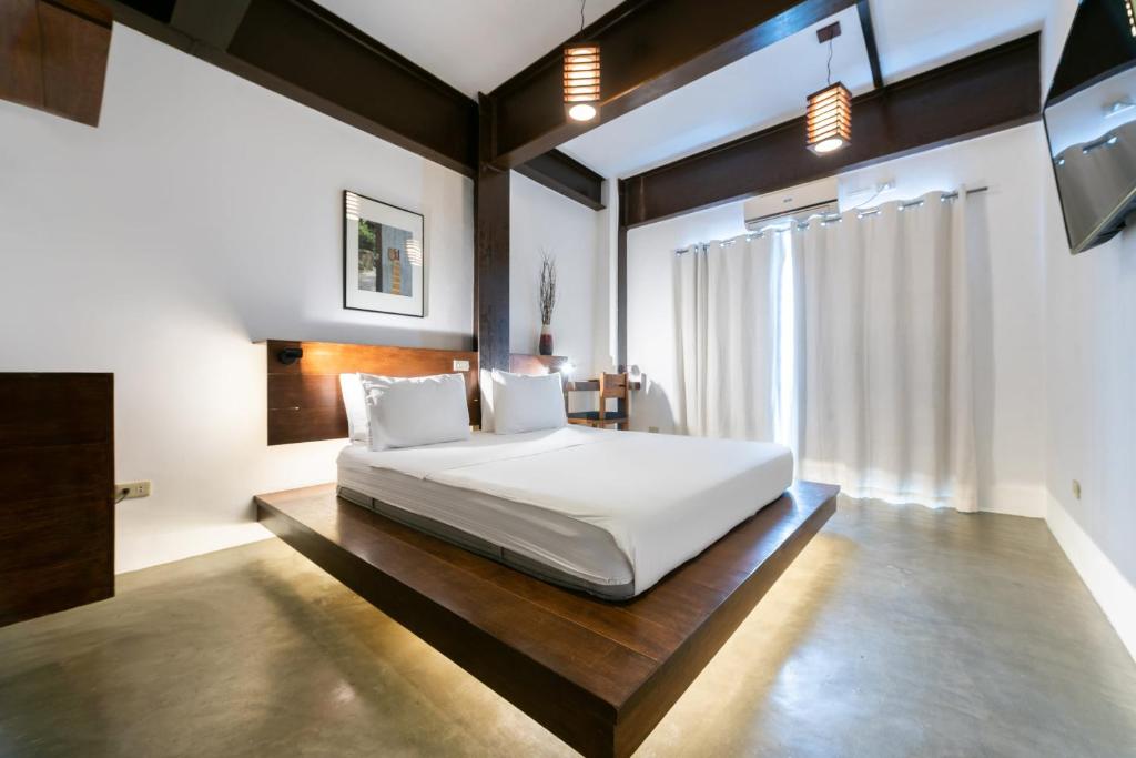 a bedroom with a white bed and a large window at Capital O 468 Element Boutique Hotel in Manila