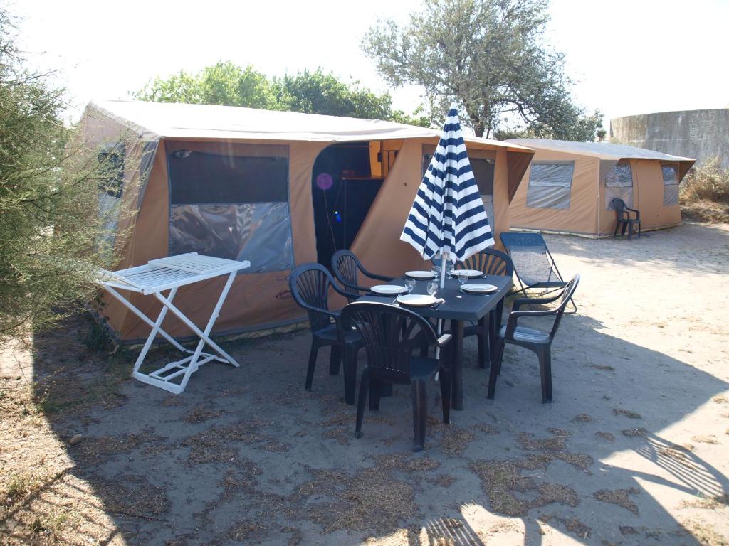 a tent with a table and chairs and a flag at Oh! Campings La Brise in Saintes-Maries-de-la-Mer