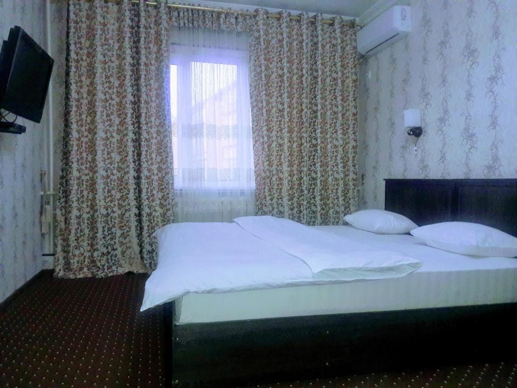 um quarto com uma cama grande e uma janela em Manzur em Fergana