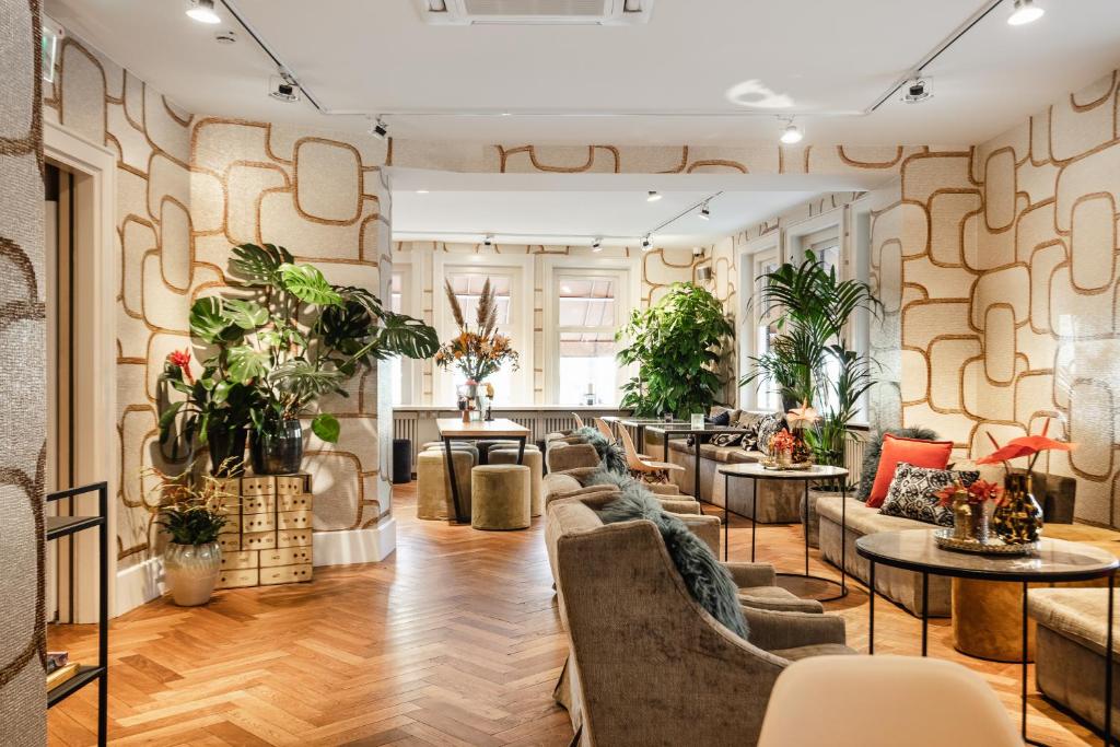 a lobby with couches and tables and plants at The Delphi - Amsterdam Townhouse in Amsterdam