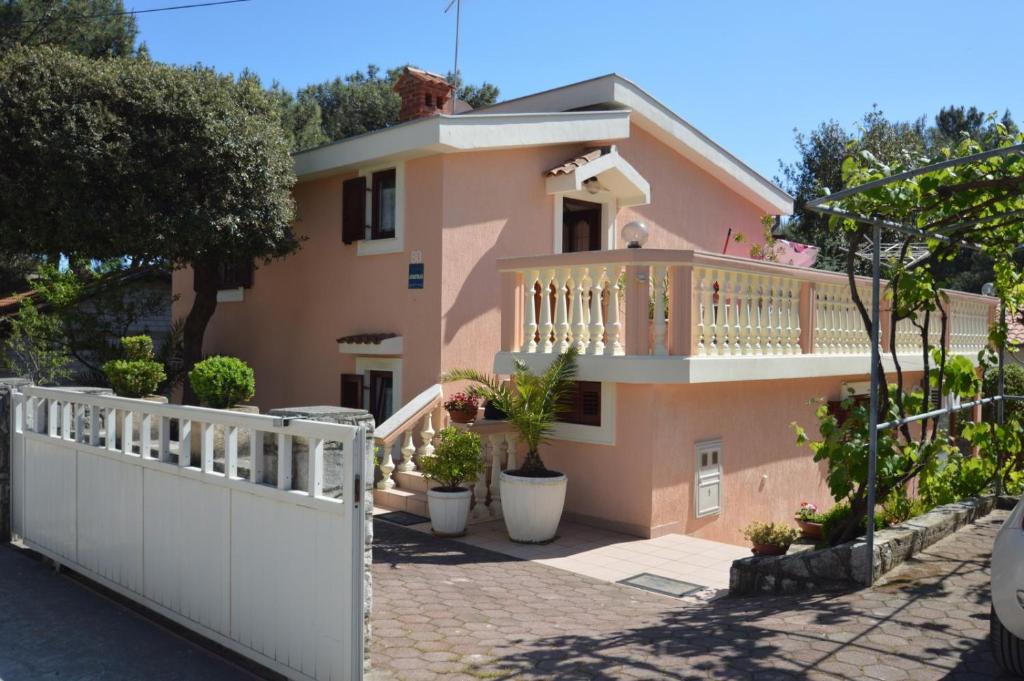 une maison rose avec une clôture blanche devant elle dans l'établissement Apartment Franka, à Mali Lošinj