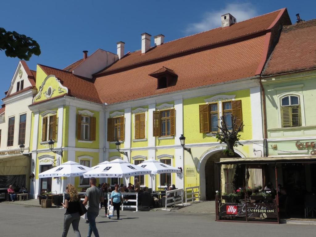 a yellow building with white umbrellas in a street at Ferdinand Apartments in Mediaş