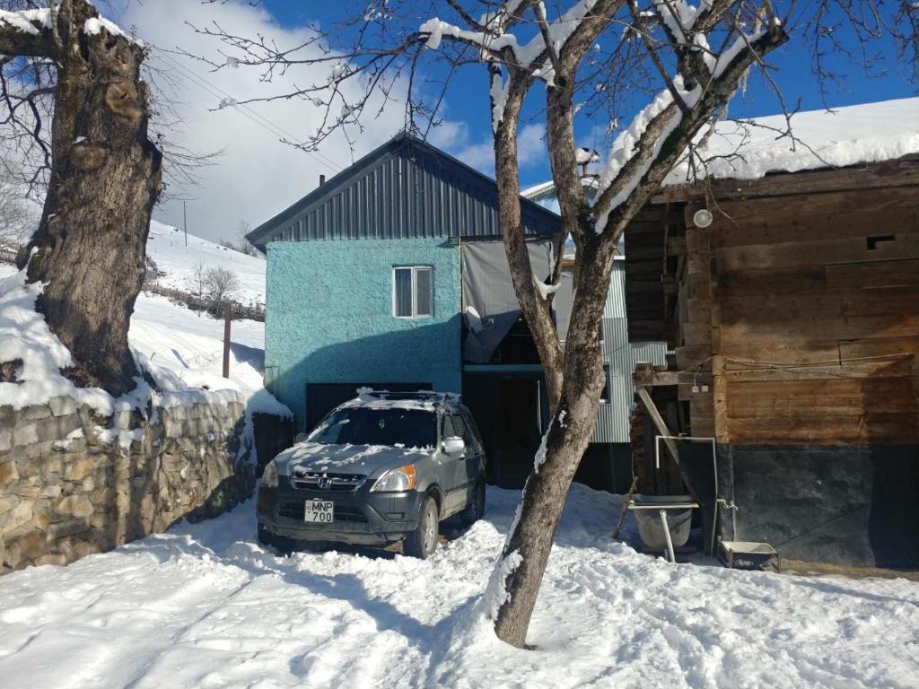 ein Auto, das vor einem Haus im Schnee parkt in der Unterkunft Guest House Luka in Danisparauli