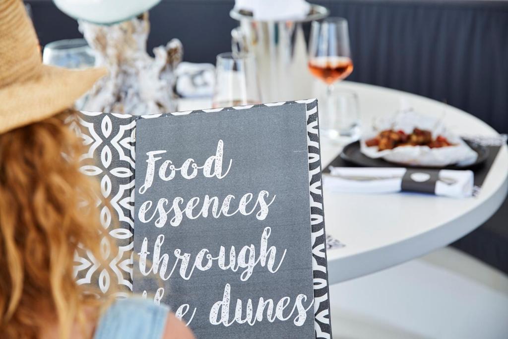a woman sitting at a table with a sign on it at White Dunes Luxury Boutique Hotel in Santa Maria