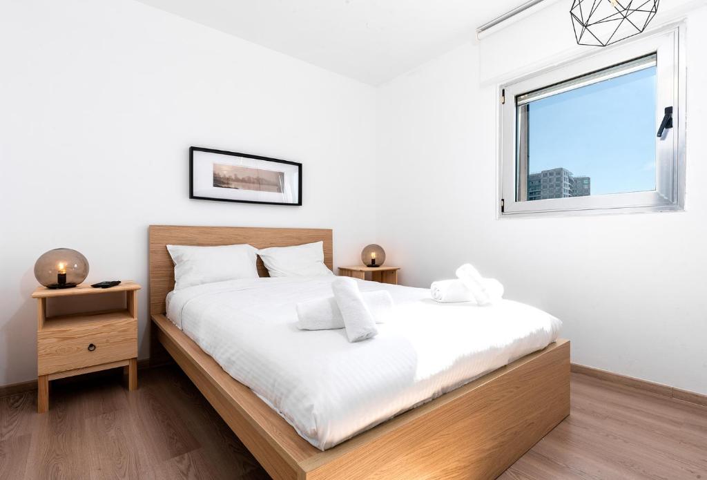 een slaapkamer met een bed en een raam bij Herzliya Marina - By Beach Apartments TLV in Herzliyya B