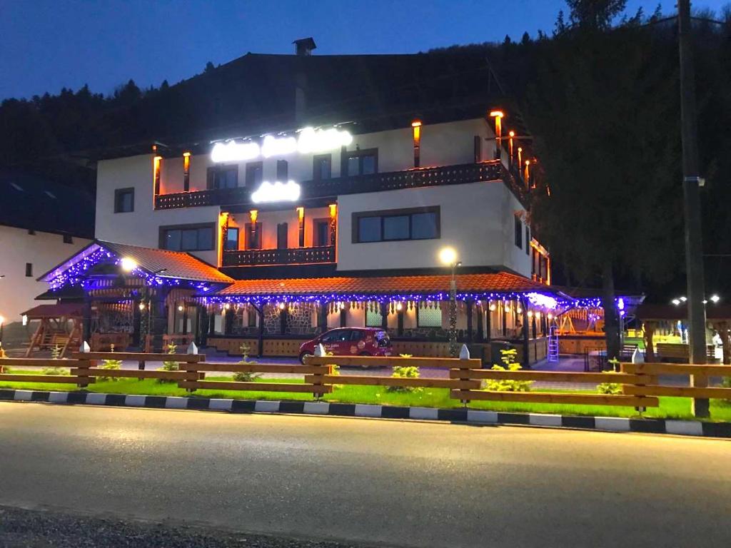 um edifício com luzes azuis em frente em Cabana Sura Getilor Arinis em Voronet