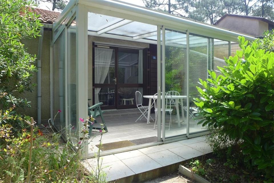 une véranda en verre avec une table et un patio dans l'établissement Réf 271, Seignosse Océan, Villa Patio au calme sous les pins, à quelques minutes de la plage et des commerces, 5 personnes, à Seignosse