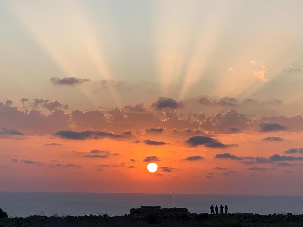 people standing on the beach watching the sunset at Fiftyfour West Boutique Living in Għarb