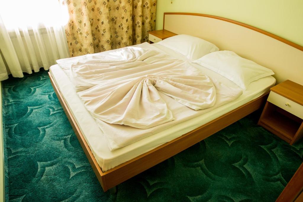 an unmade bed in a hotel room with at Struma Hotel in Pernik
