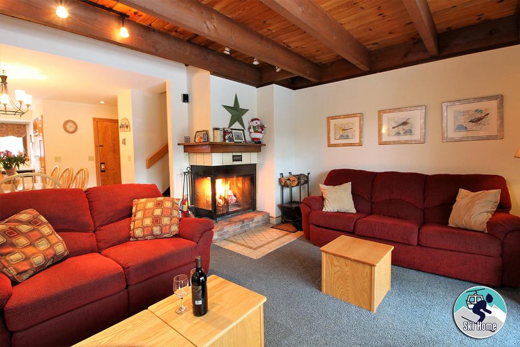 ein Wohnzimmer mit zwei roten Sofas und einem Kamin in der Unterkunft Ski home on the trail from Showshed! Or take the free shuttle A2 in Killington