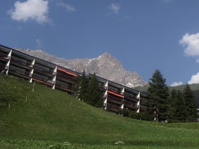 un bâtiment sur une colline avec des montagnes en arrière-plan dans l'établissement Som Barnagn 7, à Savognin